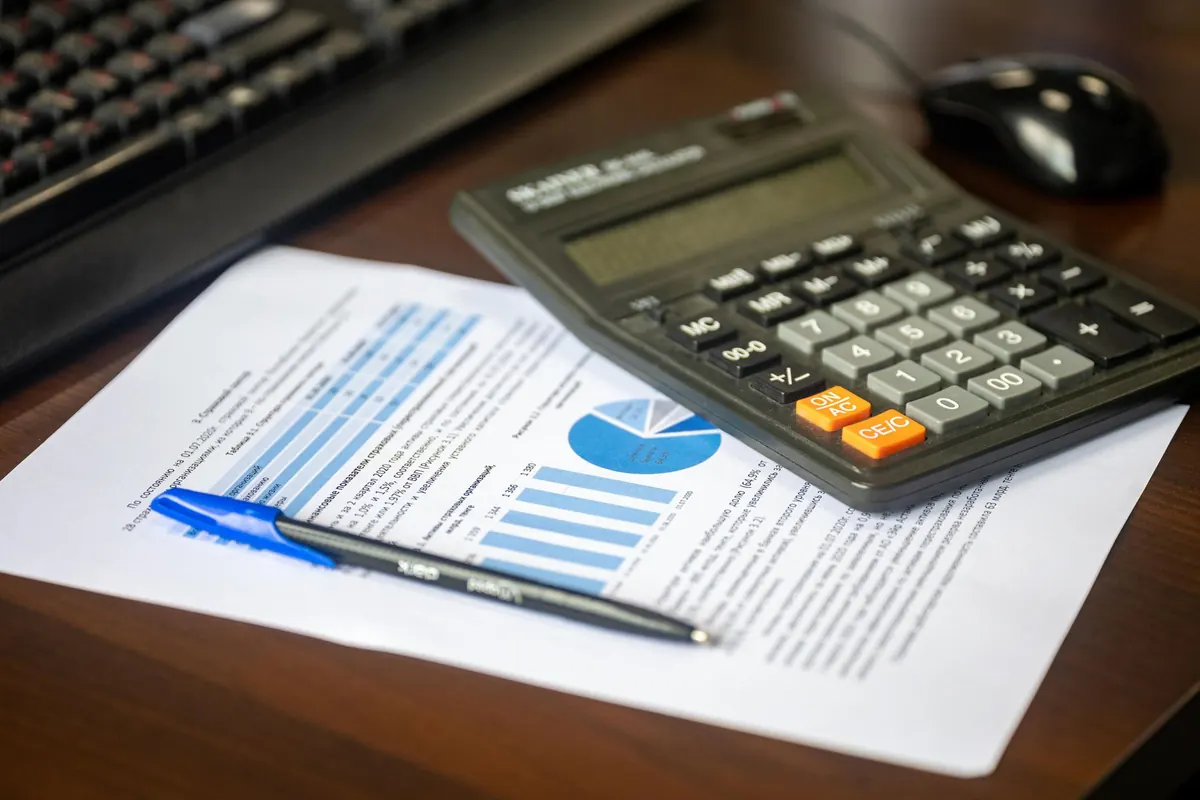 Escritorio de oficina con un informe impreso, una calculadora y un lápiz junto al teclado