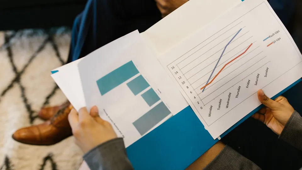 Persona revisando reportes con gráficos impresos